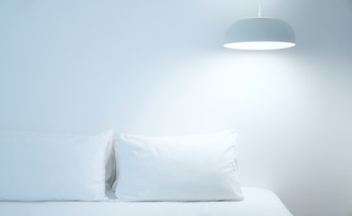 White bed sheets and pillows. Comfortable soft pillows on the bed. Close-up white bedding sheets and pillow on light wall room background. Fresh bed concept 