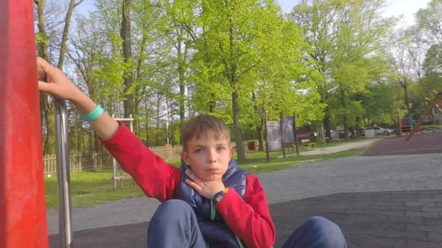 boy rides an attraction in the park, shows that he is sick, sick
