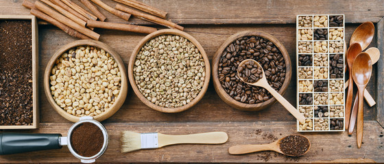 Coffee beans with ground coffee in wooden spoon and cinnamon on wooden background