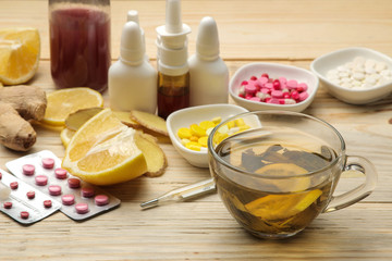 Medicines, tablets, cough syrup, thermometer and folk remedies for the treatment of influenza and the common cold on a natural wooden table.