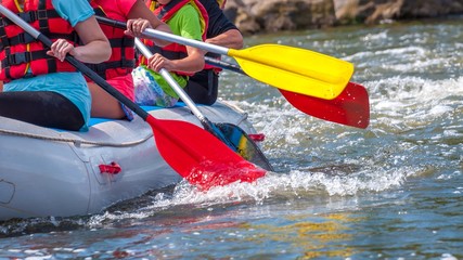 Rafting trip. Close up view of oars with splashes of water. Rowers make an effort to overcome the turbulent river. The concept of teamwork, healthy lifestyle. © Amateur007
