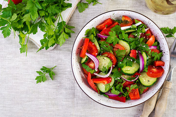 Tomato and cucumber salad with red onion, paprika, black pepper and parsley. Vegan food. Diet menu. Top view. Flat lay