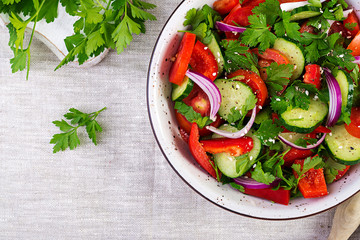 Tomato and cucumber salad with red onion, paprika, black pepper and parsley. Vegan food. Diet menu. Top view. Flat lay