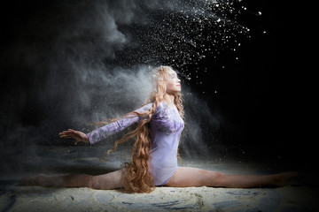 Obraz na płótnie Canvas Beautiful teen girl with long blonde curly hair in a dark room with colored lights and clouds of flour