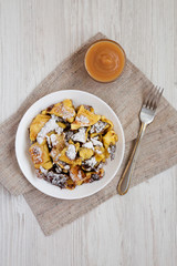 Homemade german Kaiserschmarrn pancake with apple sauce on a white wooden surface, top view. Flat lay, overhead, from above.