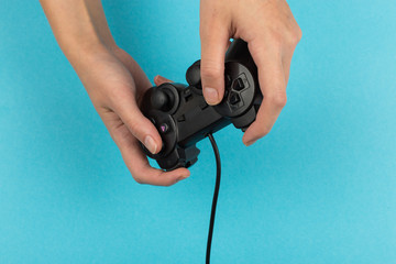 Female hands hold a gamepad on a blue background. Weekend concept, gaming hobby. Copy space.