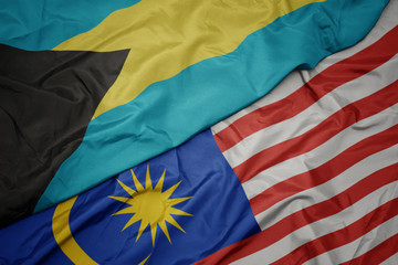 waving colorful flag of malaysia and national flag of bahamas.
