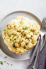 Whole baked cauliflower with spices on gray plate. Healthy vegan food concept.