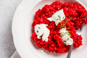 Pink beetroot risotto with feta cheese in white plate.