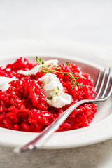 Pink beetroot risotto with feta cheese in white plate.