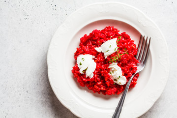 Pink beetroot risotto with feta cheese in white plate.