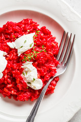Pink beetroot risotto with feta cheese in white plate.