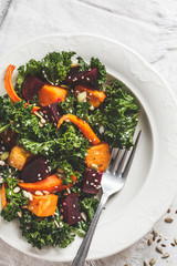 Kale salad with baked vegetables in white plate.