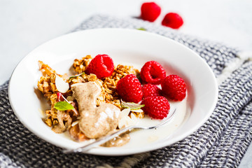 Healthy vegan breakfast - baked oatmeal crumble with berries and nut butter in a white plate.