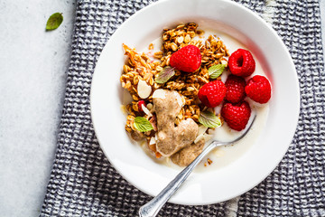 Healthy vegan breakfast - baked oatmeal crumble with berries and nut butter in a white plate.
