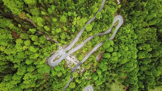 Drone footage of curvy mountain side road in the middle of thich green pine tree forest hill near Trenta Slovenia, Europe in Triglav National Park