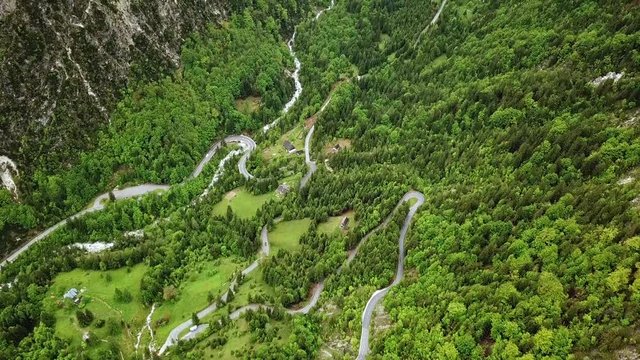Drone footage of curvy mountain side roads surrounded by green pine tree forest mountains in beautiful valley near Trenta Slovenia, Europe in Triglav National Park