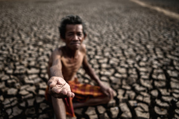 An elderly man was sitting asking for rain in the dry season, global warming, selective focus