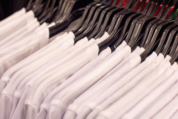 Close up of white t-shirts on a clothes rack in retail store.