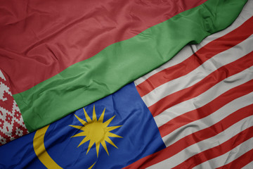 waving colorful flag of malaysia and national flag of belarus.