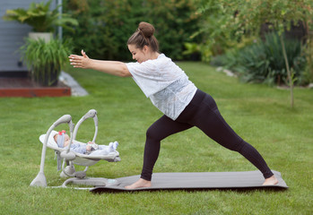 Young happy smiling mother excercising fitness yoga in the garden. Healthy lifestyle and pregnancy weight loss concept. 