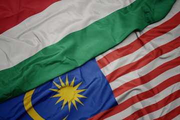Obraz premium waving colorful flag of malaysia and national flag of hungary.