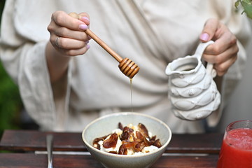 Honey dripping from honey dipper in wooden bowl. Close-up. Healthy organic