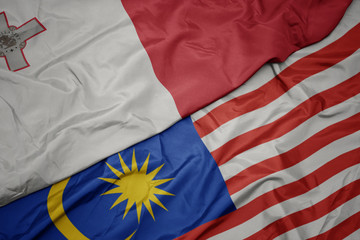 waving colorful flag of malaysia and national flag of malta