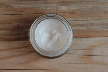 A jar with cosmetic cream stands on a wooden background