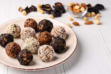 Energy balls of nuts, oatmeal and dried fruits on a plate on a white background, horizontal orientation