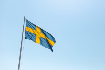 Flag of Sweden flying in the wind against the blue sky in summer day, copy space