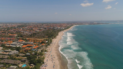Fototapeta na wymiar Aerial view sand beach with resting people, hotels and tourists, sun umbrellas, Bali, Kuta. surfers on water surface. Seascape, beach, ocean, sky sea Travel concept
