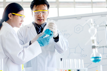 Two scientists are working in laboratory. Young female researcher and her senior supervisor are doing investigations with test tubes.