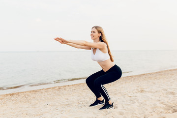 Young beautiful athletic girl doing sports outdoors, at sea