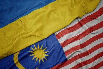 waving colorful flag of malaysia and national flag of ukraine.