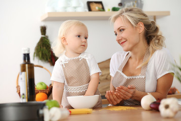 Happy mother and little daughter cooking in kitchen. Spending time all together, family fun concept