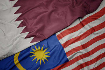 Obraz premium waving colorful flag of malaysia and national flag of qatar.
