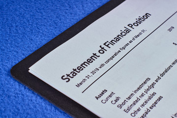 Sheet a statement of financial position in a black folder and pen on a blue velvet background