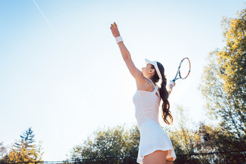 Woman serving the ball in tennis match