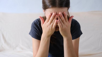 Depressed anxious worried young woman sitting on couch at home. Frustrated confused female feels unhappy, problems in personal life, quarrel break up with boyfriend and unexpected pregnancy concept