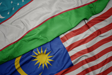 waving colorful flag of malaysia and national flag of uzbekistan.