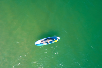 Summer Vacations. Beautiful Young Woman Relaxing on the SUP at Turquoise Water. Beauty, Wellness. Recreation.