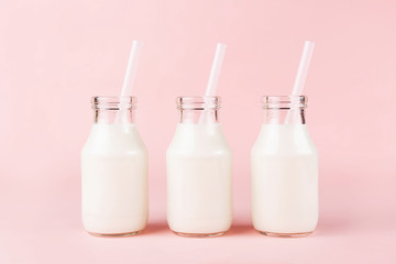 Three bottles of milk of yogurt on pink background.