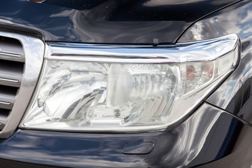 Front headlight view of car in black color after cleaning before sale in a sunny day on parking