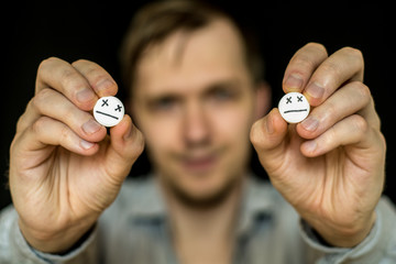 The man is holding two large white pills.  On tablets drawn emoticons.