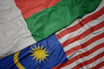 waving colorful flag of malaysia and national flag of madagascar.