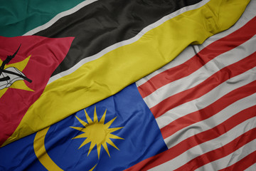 waving colorful flag of malaysia and national flag of mozambique.