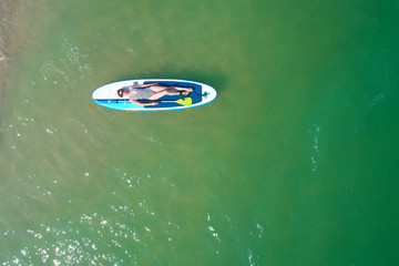Fototapeta na wymiar Summer Vacations. Beautiful Young Woman Relaxing on the SUP at Turquoise Water. Beauty, Wellness. Recreation.