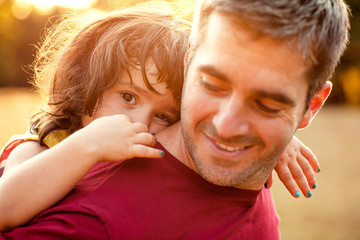 Fototapeta premium Portrait of father holding daughter in his hands and hugging each other outdoors.