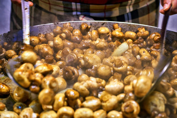 Large steel pan with mushrooms on a market. Champignons with garlic.